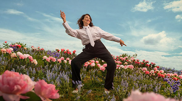 Heather is dancing with arms outstretched in a field of pink flowers
