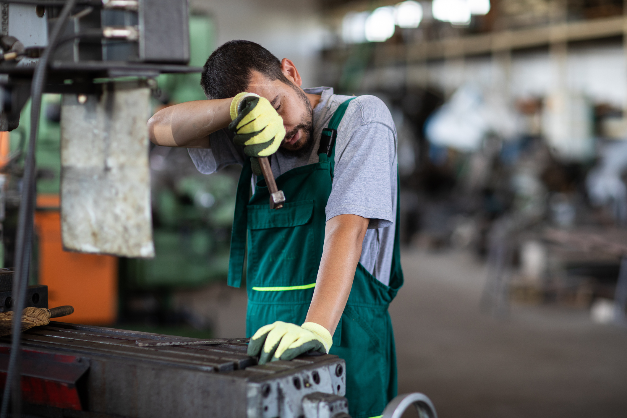 Southern Cross - A man wipes his face while working at a machine A man wipes his face while working at a machine