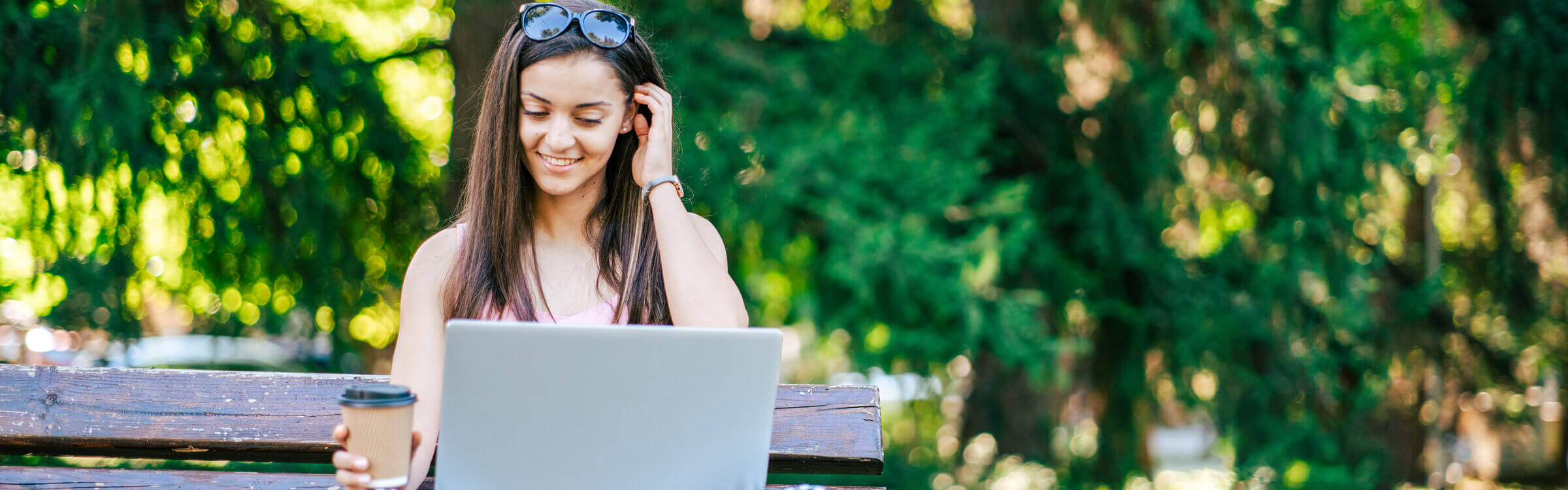A woman sitting on a park bench using her laptop