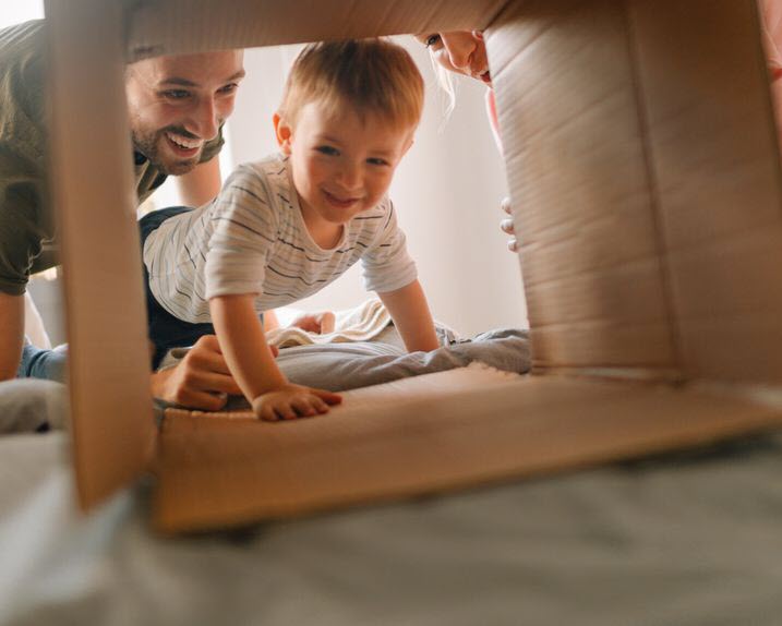A mother and father and their child playing pretend with a cardboard box